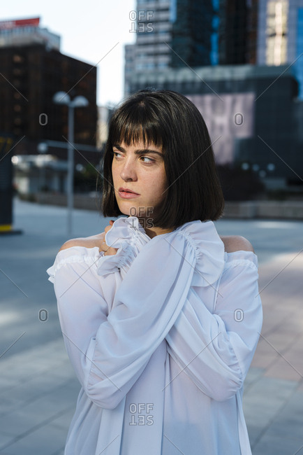 Young brunette woman looking away with crossed hands on chest