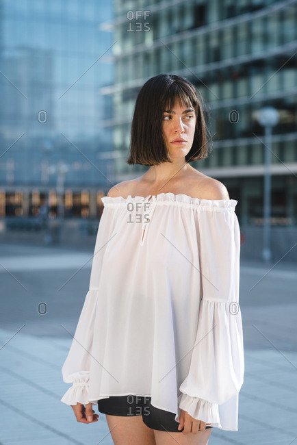 Contemporary young brunette woman looking away on urban scenery