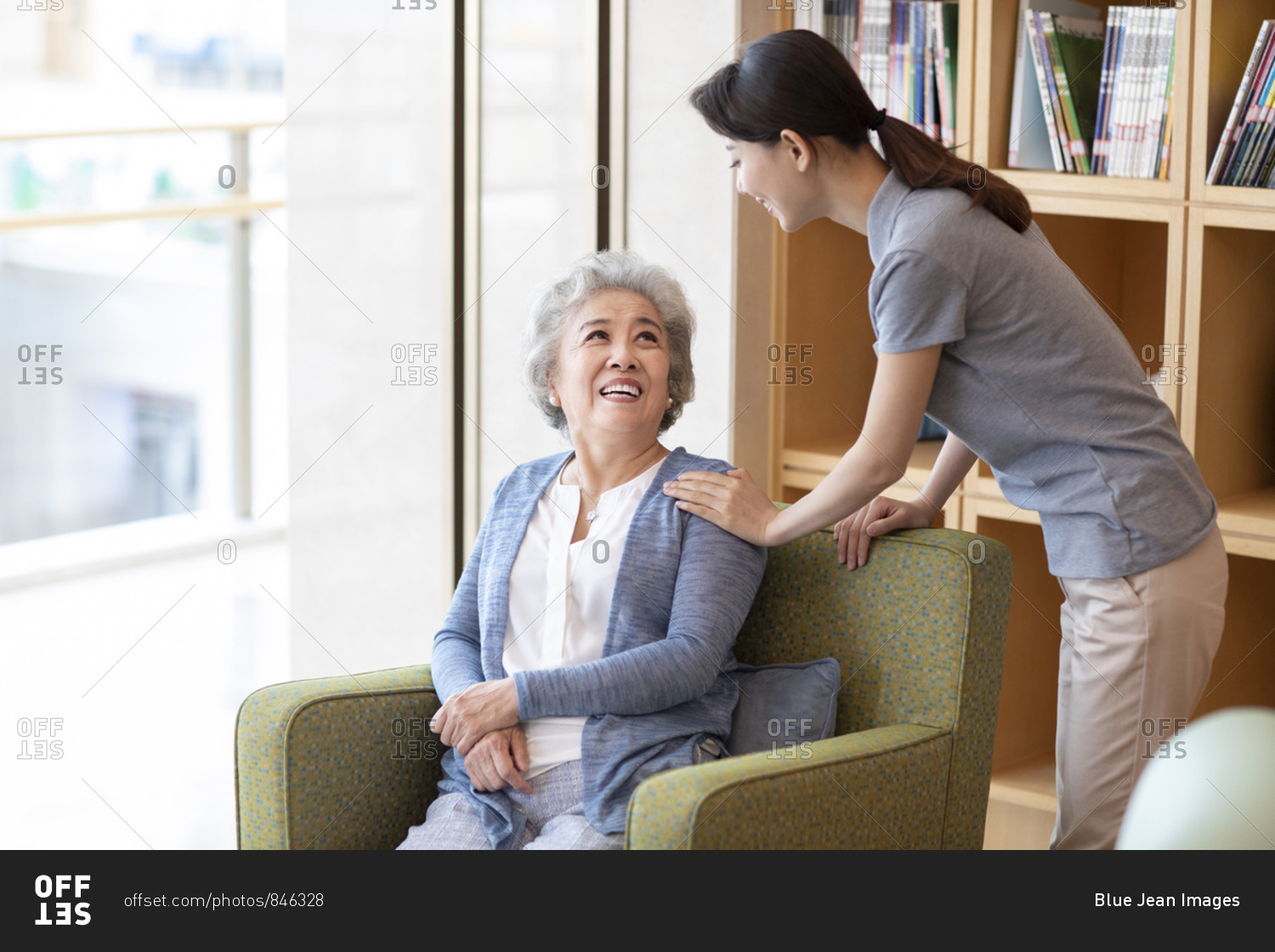 Chinese nursing assistant taking with senior woman in nursing home