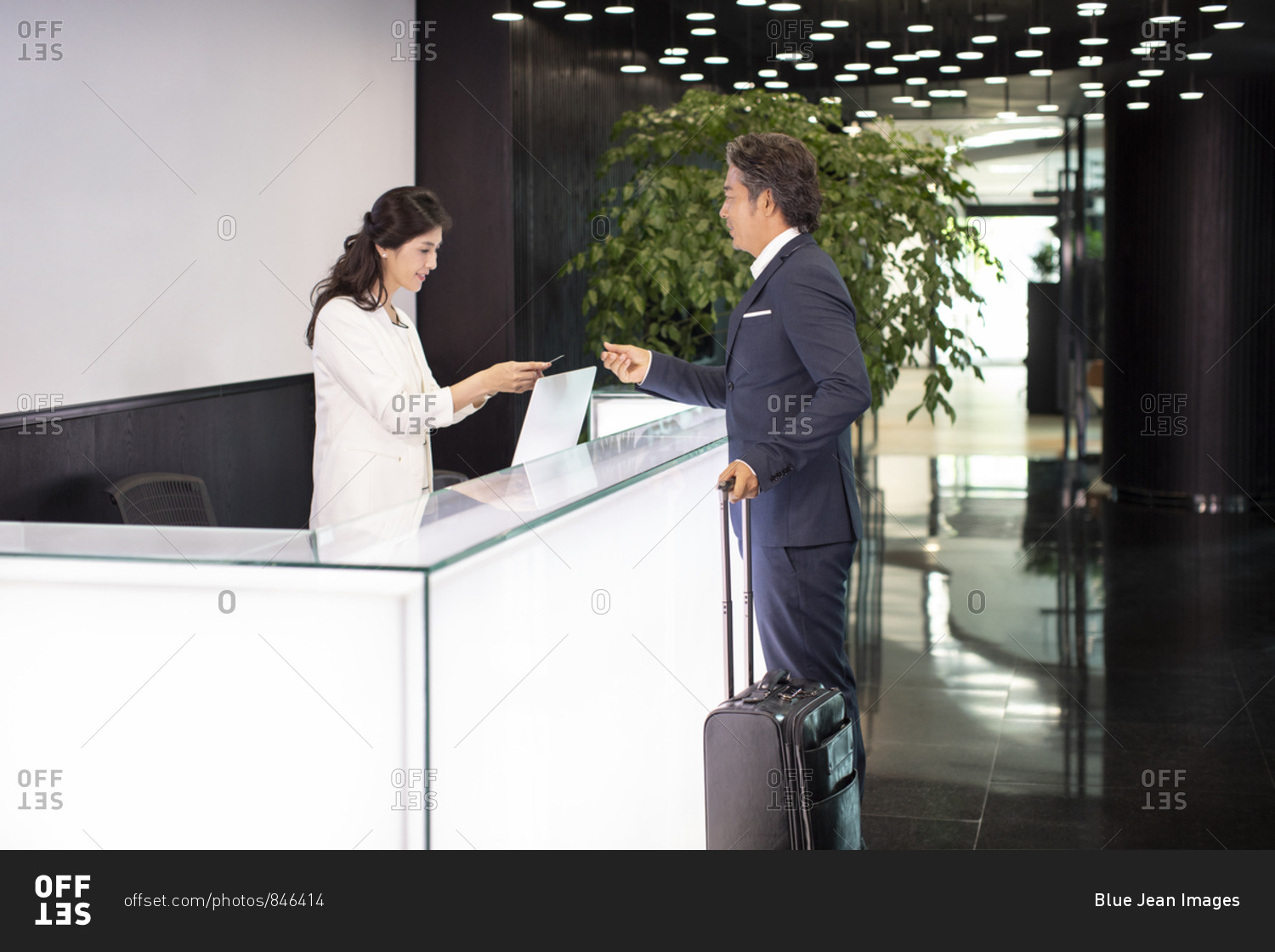 Mature Chinese businessman giving business card to receptionist