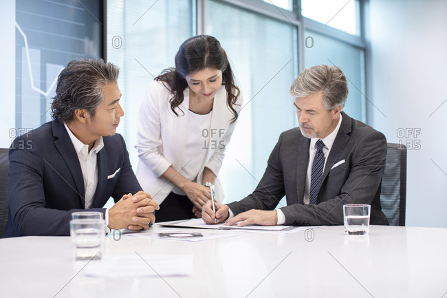Business people signing contract in conference room