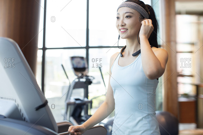 Young Chinese woman running with wireless headphone at gym