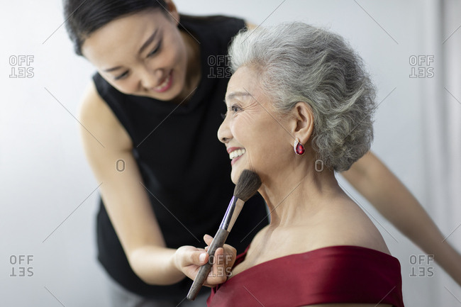 Chinese makeup artist applying makeup on senior woman