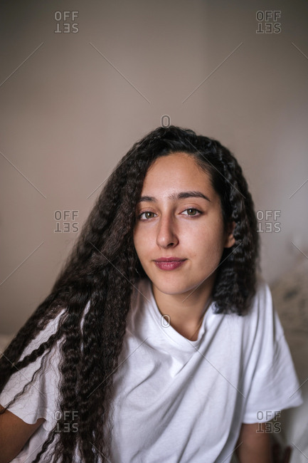 Portrait of teen with afro hair is sitting on a bed