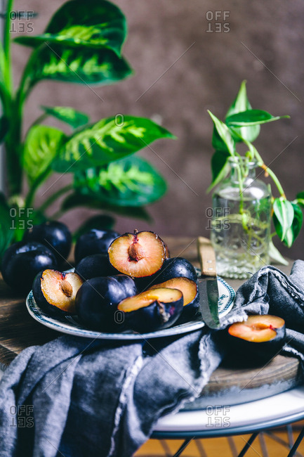 Plums on a plate beside a plant