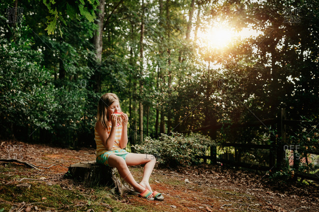 Girl eating watermelon in the forest