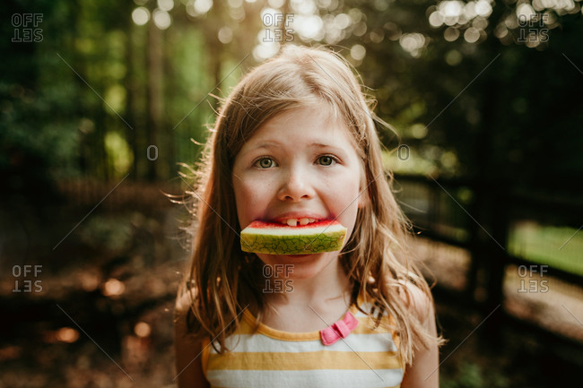 Close up of a girl eating watermelon in the forest