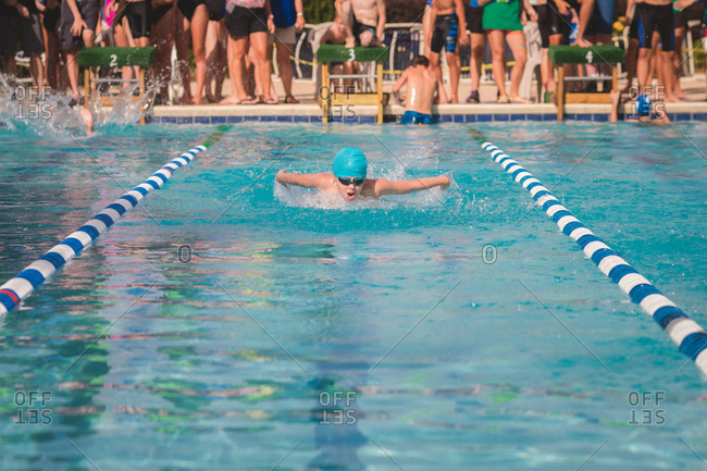 Boy wearing blue swim cap racing at a swim meet