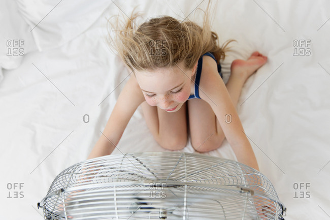 Overhead view of blonde girl facing electric fan