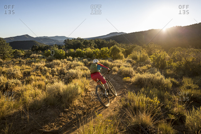 A woman riding a mountain bike outdoors just before sunset.