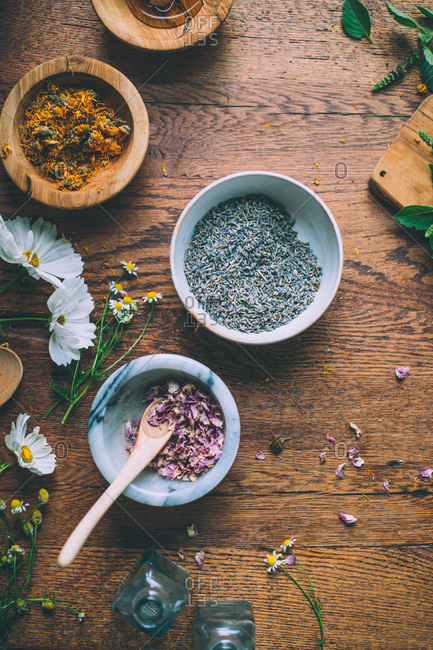 Bowls of lavender and rose petals on wood table.