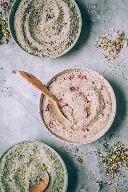 Bowls of powdered herbs on grey plaster background.