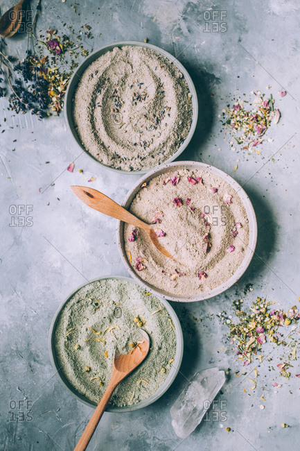 Bowls of powdered herbs on grey plaster background.