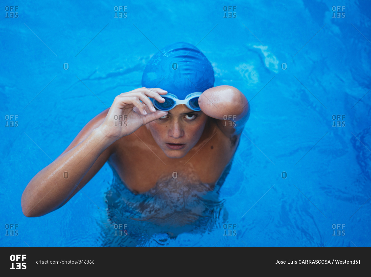 Portrait of young paralympic swimmer putting on swimming goggles