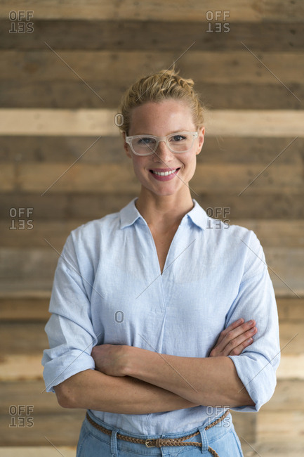 Portrait of blond woman- arms crossed- wooden background