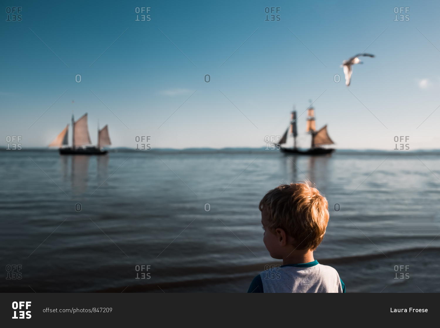 Little boy watching pirate ships in the ocean