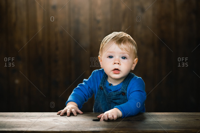 Portrait Of A Cute Baby With Blonde Hair And Blue Eyes Wearing