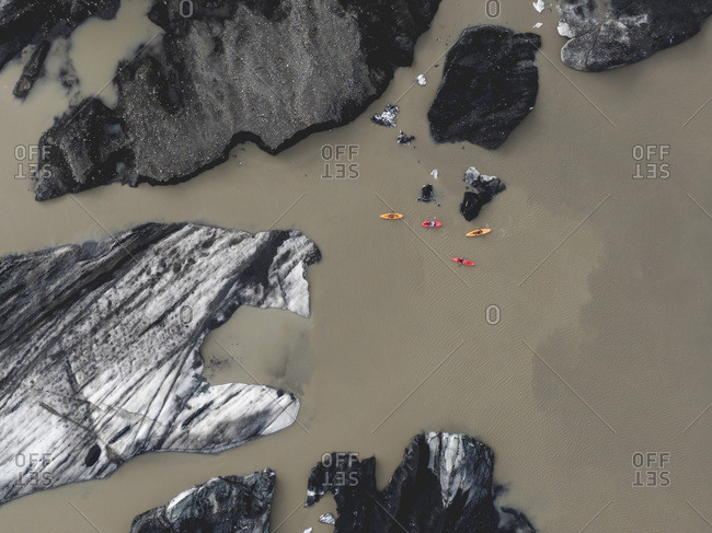 Aerial view of canoes and iceberg in lagoon with dirty water