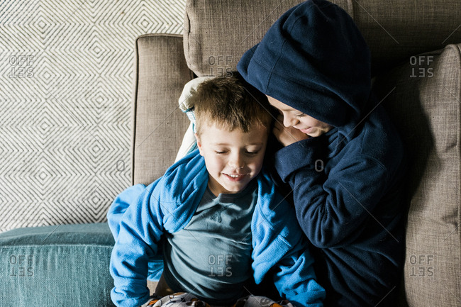 Two boys lie on the couch together