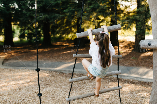 Girl on playground climbs a wooden ladder