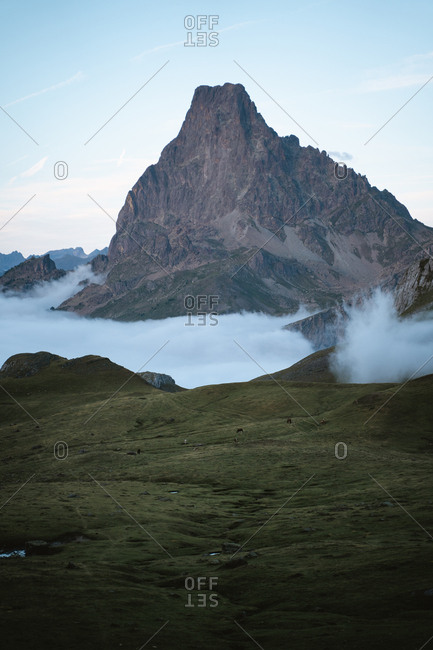 Beautiful twilight in Pyrenees, Ossau valley covered in clouds and Pic du Midi D'Ossau above them