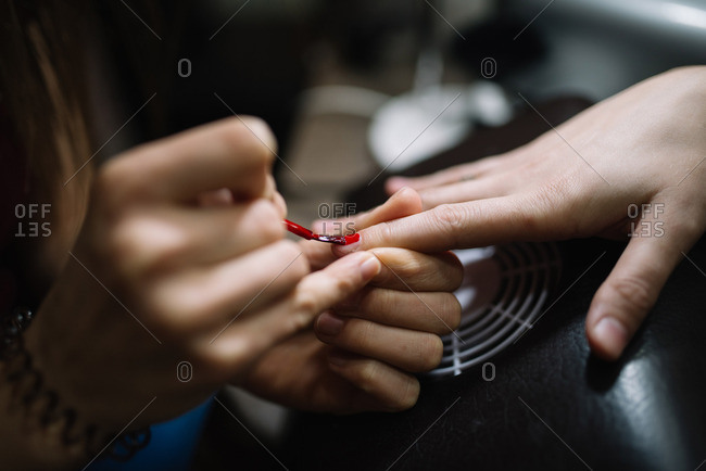 Woman red paint on client's nails.