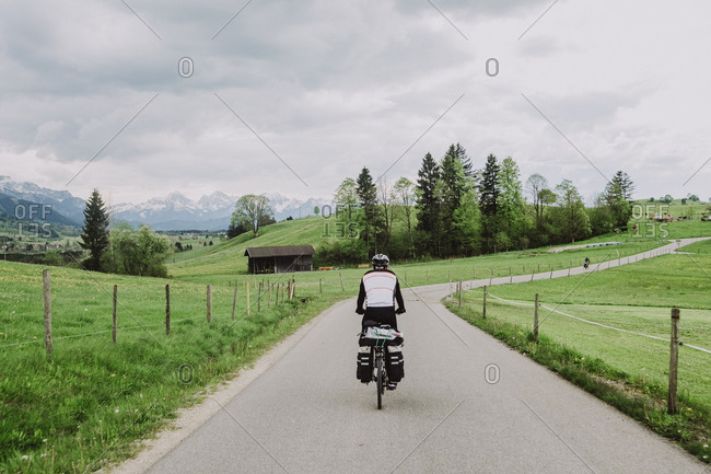 A cyclist riding in a beautiful landscape near to The Alps