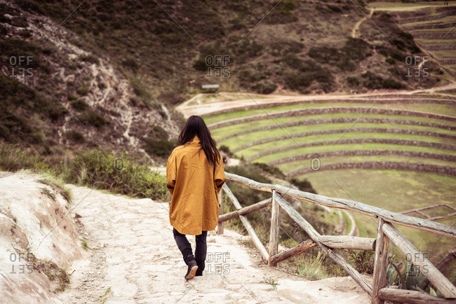 Person in jacket walks down steps of archaeological Inca ruins site