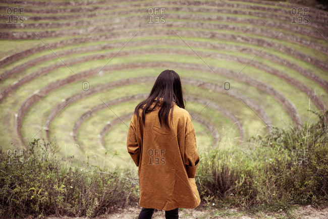Person in jacket walks down steps of archaeological Inca ruins site