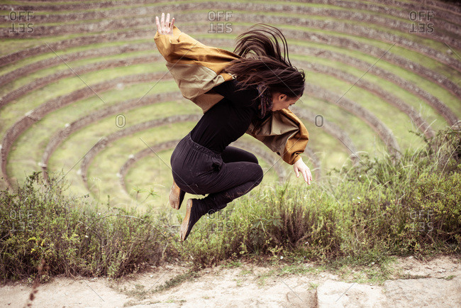 girl jumps in circle of archaeological Inca ruins sight