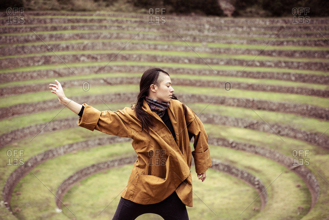 Dancer in jacket in center of ancient stone circles from Inca ruins