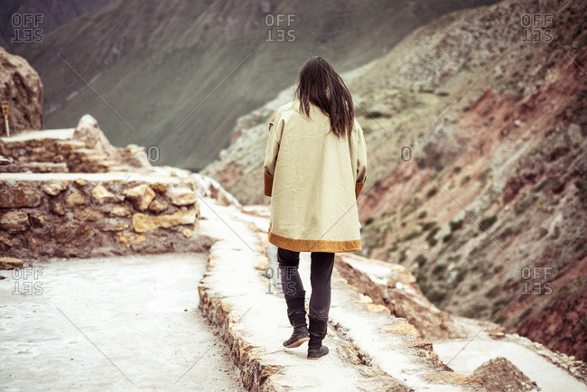 Androgynous dancer walks in salt farm on mountain side