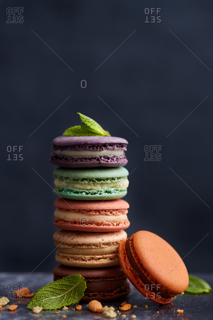 Colorful macarons and green leaves stacked on a marble background