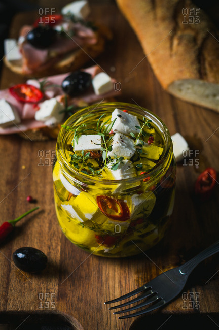 Marinated goat cheese with fresh herbs, spices and chili peppers in olive oil