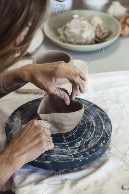 Female potter making a heart shaped pot with clay in workshop