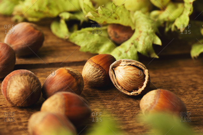 Close up of hazelnuts on wooden surface with one cracked open nut