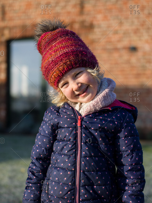 Portrait of a smiling little girl in winter light dressed with a hat and a thick coat