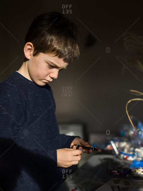 Little boy concentrating while building with a toy building blocks