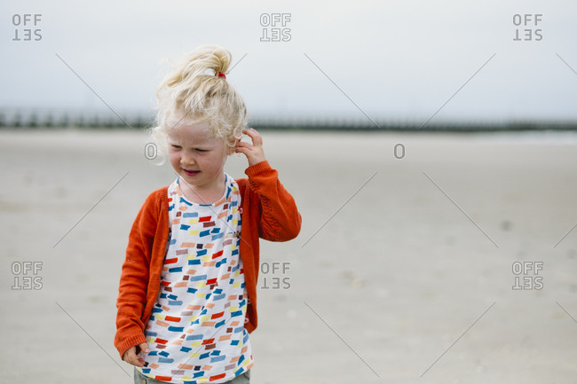 Little girl on the beach dressed in orange on a late summer afternoon