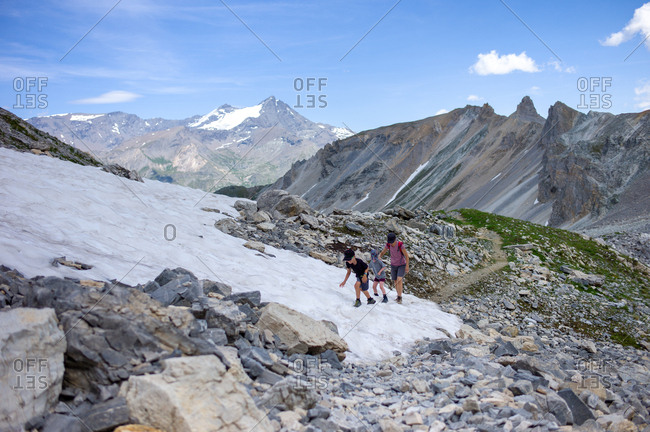 Hiking family crosses a snow bank in an alpine landscape on a beautiful summer in Northern Europe
