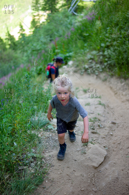 Little girl walking up a steep path covered in dirt during a hike in high mountains in Northern Europe