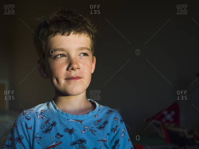 Portrait of a young boy smiling lightly with a grazing light of window