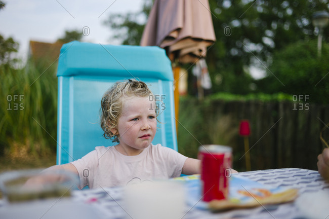 Little girl sitting at outdoor table in a vacation environment