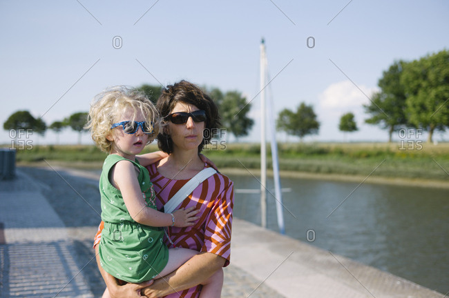 Mother with daughter in the arms standing by the sea