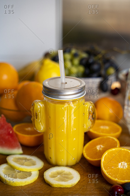 Orange smoothie on kitchen table with various fruit