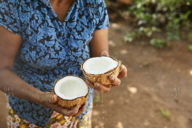 Woman holding two halves of fresh coconut- Sri Lanka