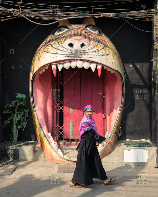 Dhaka, Bangladesh - January 30, 2019: Muslim Woman walking in front of a tiger-shaped door, in Dhaka