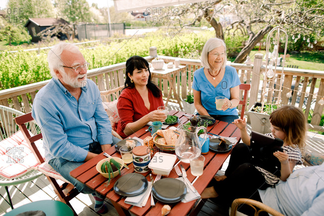 Multi-generational family enjoying food at table in patio