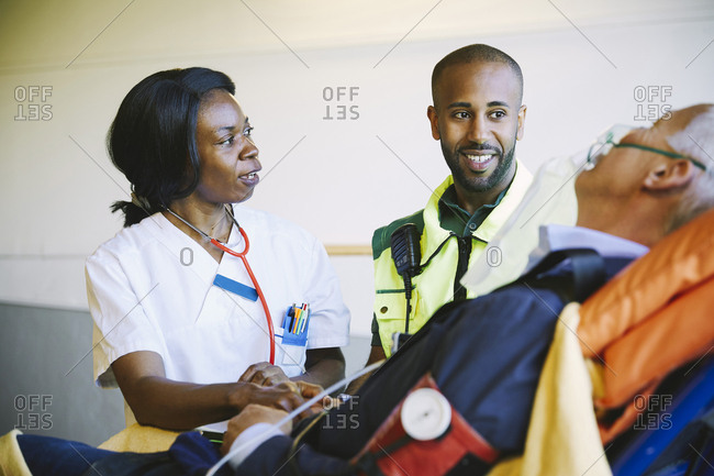 Doctor talking to paramedic while treating mature businessman on hospital gurney
