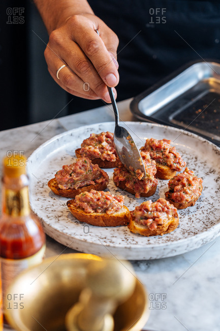 Chef preparing appetizers of small bread slices with meat